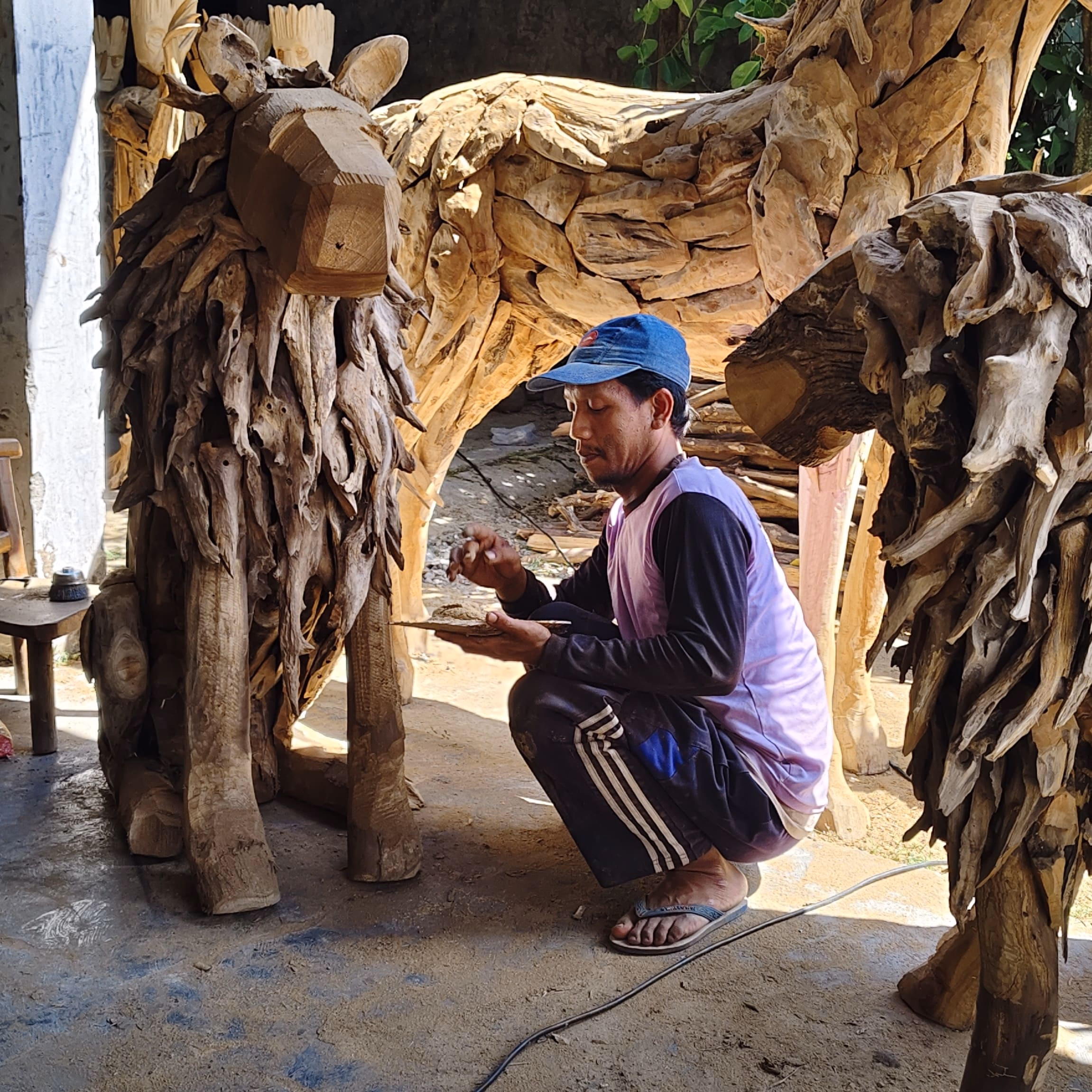 Indonesian artisan handcrafting teak root sculpture